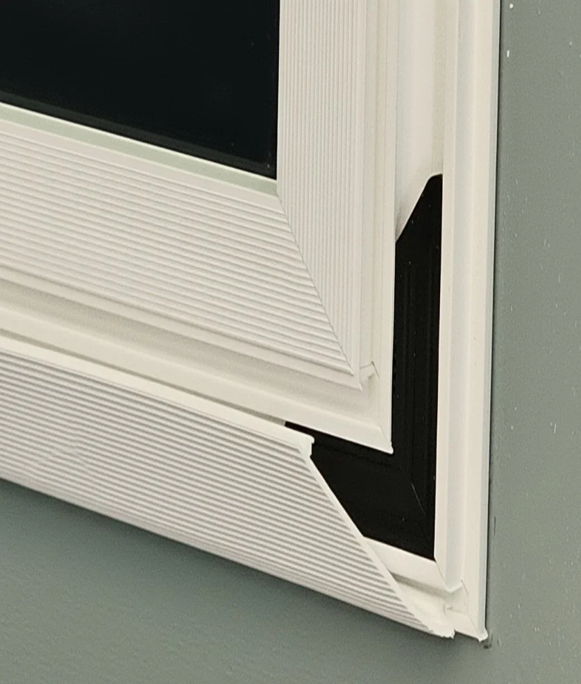 Close-up of white PVC mirror frame corner showing ribbed texture and molding